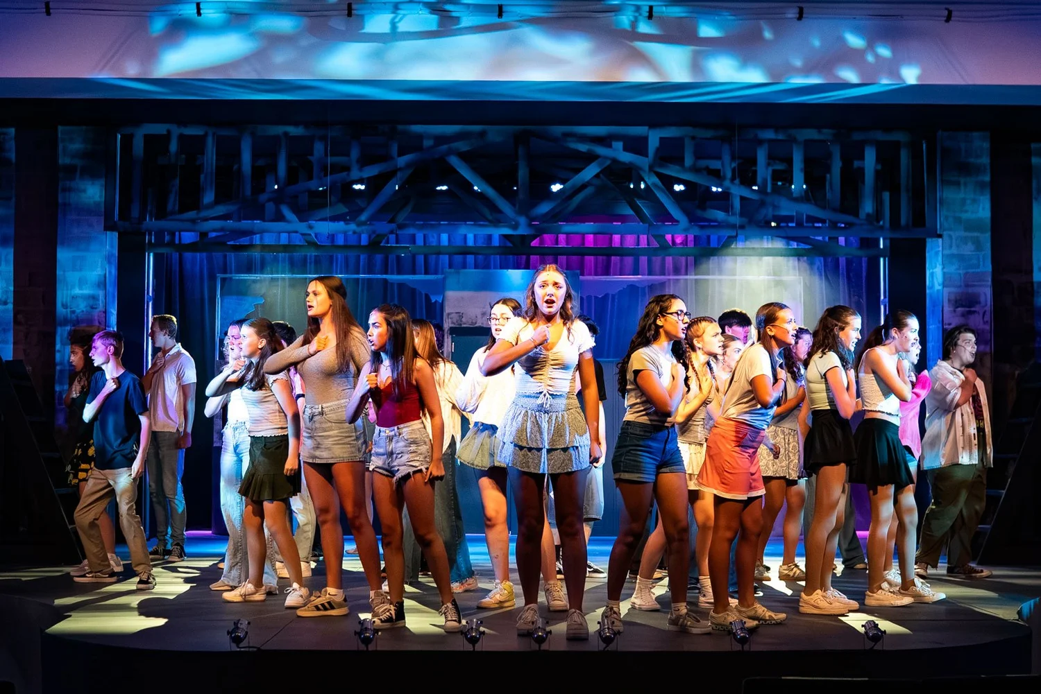 An ensemble sings beneath blue lighting